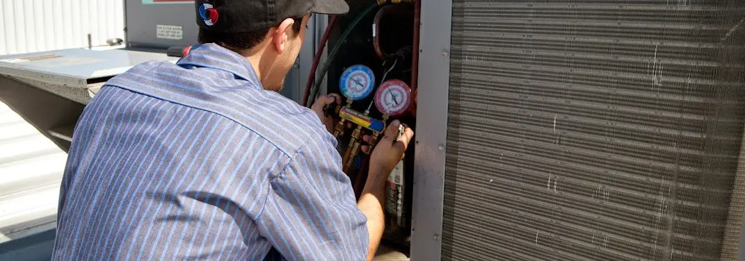 HVAC technician servicing a condenser unit in Lancaster